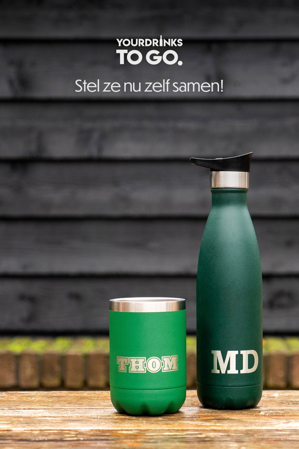 Twee groene thermosflessen gegraveerd met naam op een houten tafel met zwarte achtergrond